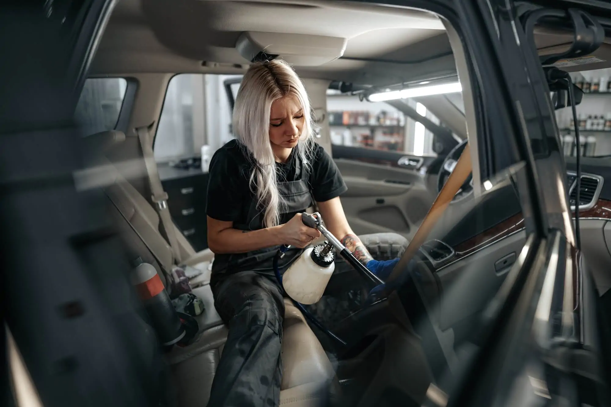 woman cleaning car salon with polishing spray in car detailing service